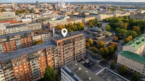 An urban landscape with a mix of residential and commercial buildings, a prominent red-brick building in the foreground, and a river in the background. - 3BR Loft Penthouse w/ Balcony & Sauna (Tampere)