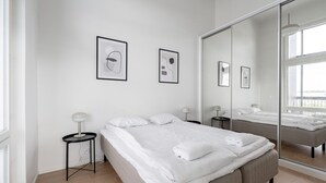 A modern hotel room with a large bed, a bedside table, a mirror, and framed artwork on the wall. - 3BR Loft Penthouse w/ Balcony & Sauna (Tampere)