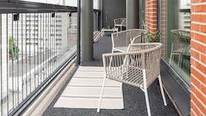 A balcony with wicker chairs, a small table, and a view of the cityscape. - 3BR Loft Penthouse w/ Balcony & Sauna (Tampere)