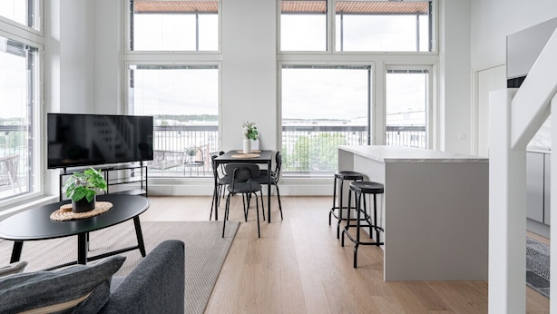 A modern living room with a TV, dining area, and bar. - 3BR Loft Penthouse w/ Balcony & Sauna (Tampere)