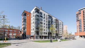 Un immeuble résidentiel à plusieurs étages, doté de balcons, d’un espace de stationnement et surplombant un ciel dégagé.
