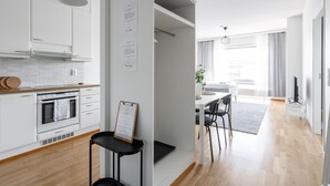Une cuisine moderne avec des meubles blancs, un four encastré et un coin repas comprenant une table et des chaises.