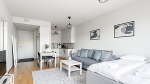 Un appartement moderne et bien éclairé, comprenant un coin repas, une kitchenette et un grand lit.