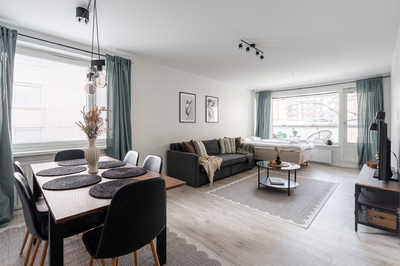 A modern living room with a dining area, a sofa, and a TV.