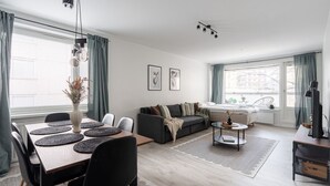 A modern living room with a dining area, a sofa, and a TV.