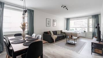A modern living room with a dining area, a sofa, and a TV.