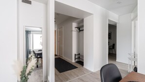 A modern interior with a dining area, a hallway leading to a bedroom, and a bathroom with a towel rack.