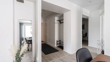 A modern interior with a dining area, a hallway leading to a bedroom, and a bathroom with a towel rack.