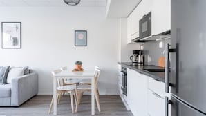 A modern kitchen with white cabinets, a stainless steel refrigerator, and a coffee maker on the counter.