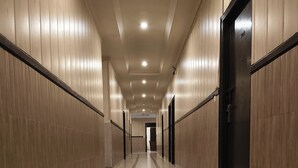 A long, narrow hallway with wooden paneling on the walls and a tiled floor with a red stripe. - Park Square Hotel And Banquet  (Moradabad)