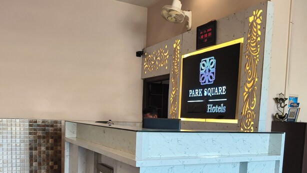 A reception desk with a digital clock and a sign for Park Square Hotels. - Park Square Hotel And Banquet  (Moradabad)