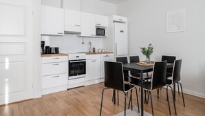 A modern kitchen with white cabinets, a built-in oven, and a dining area with a black table and chairs. - Renovated 1BR at Main Square | Sauna & Parking (Tampere)