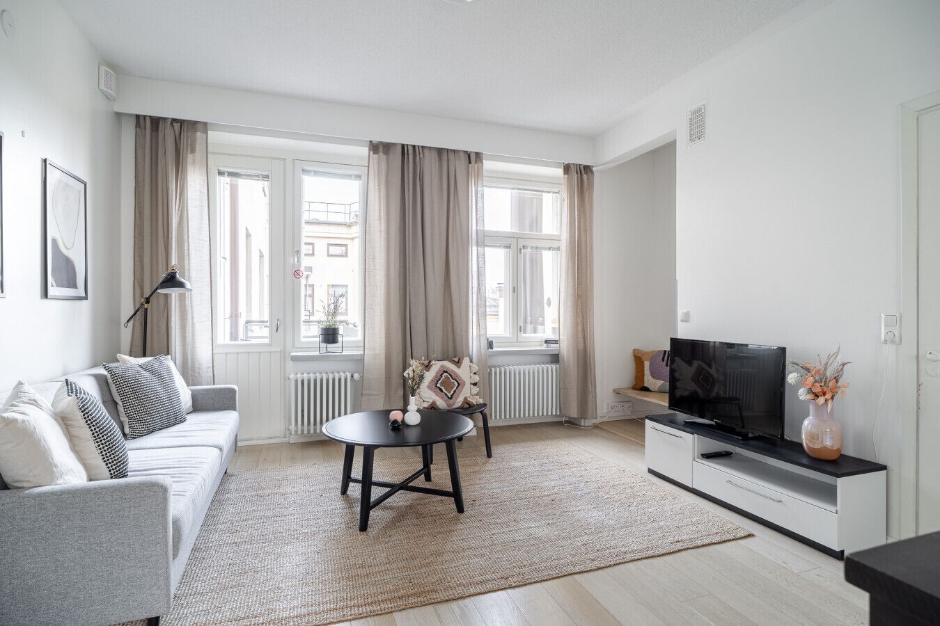 A modern living room with a sofa, a small round table, a TV, and a radiator.