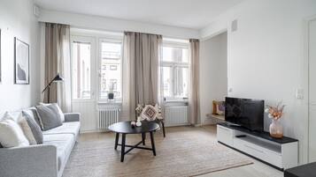 A modern living room with a sofa, a small round table, a TV, and a radiator.