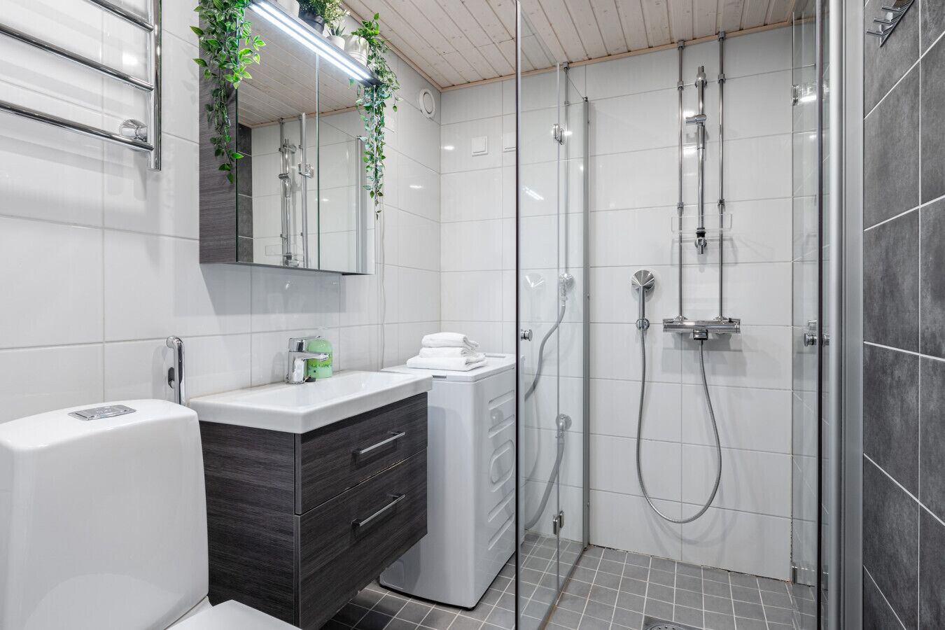 A modern bathroom with a glass shower enclosure, a vanity with a dark wood cabinet, and a white toilet.