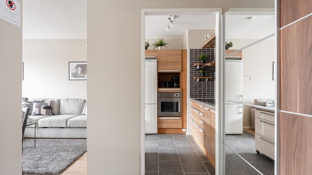A modern kitchen with wooden cabinets, a built-in oven, and a tiled backsplash.