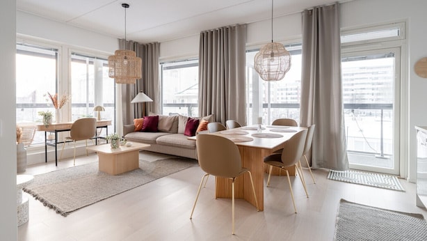 A modern living room with a sofa, dining table, chairs, and large windows.
