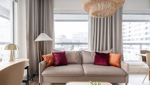 A modern living room with a beige sofa, a floor lamp, and a woven light fixture.