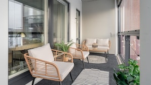 A balcony with wicker furniture, a round table, and a potted plant.