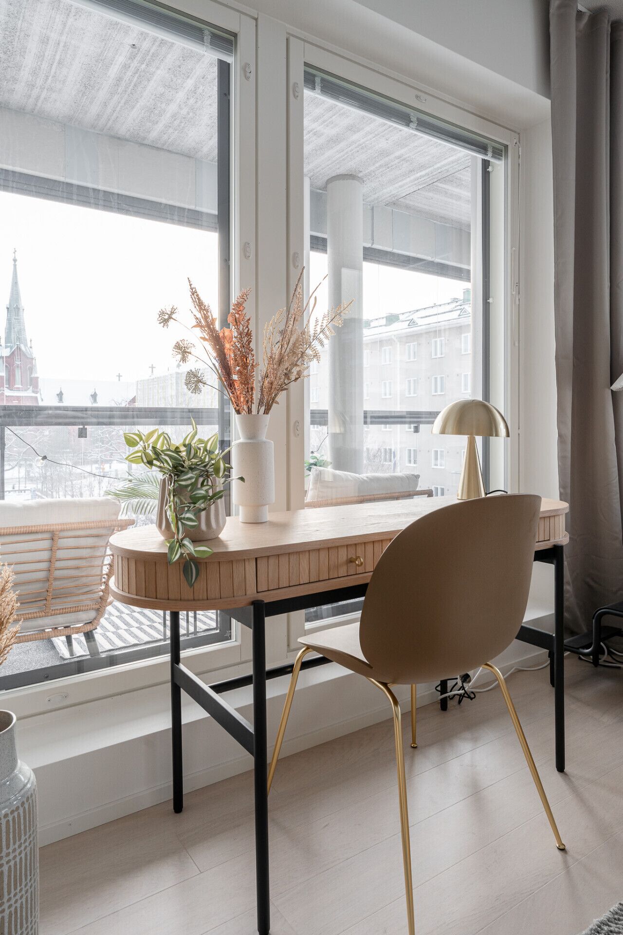 Un espacio de trabajo moderno con un escritorio de madera, una silla y ventanas amplias que ofrecen vistas a la ciudad.