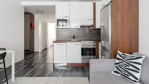 A modern kitchen with white cabinets, a built-in oven, and a stainless steel refrigerator.