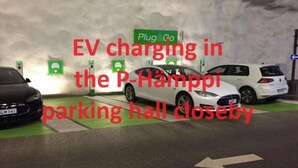 A parking area with EV charging stations labeled "Plug&Go" and a white car parked nearby.