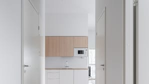 A hallway leading to a kitchen with wooden cabinets, a microwave, and a sink.