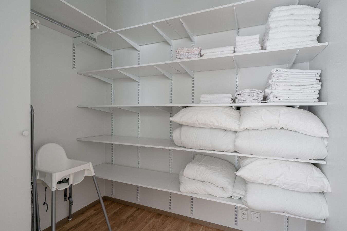 A storage area with white shelves holding folded towels and pillows.