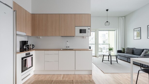 A modern kitchen with wooden cabinets, a built-in microwave, and a coffee maker.