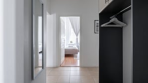 A hallway leading to a bedroom with a bed, a wardrobe, and a framed picture on the wall.