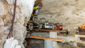Ein Weinkeller mit Flaschen auf Regalen und einer Weinpumpe an der Wand.
