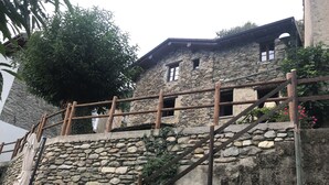 Ein Steinhaus mit einer Holztreppe und einem Geländer.