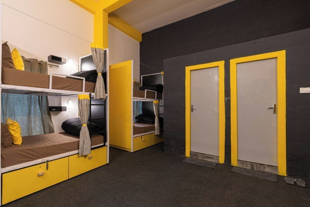 A dormitory room with bunk beds, a desk, and a wardrobe.