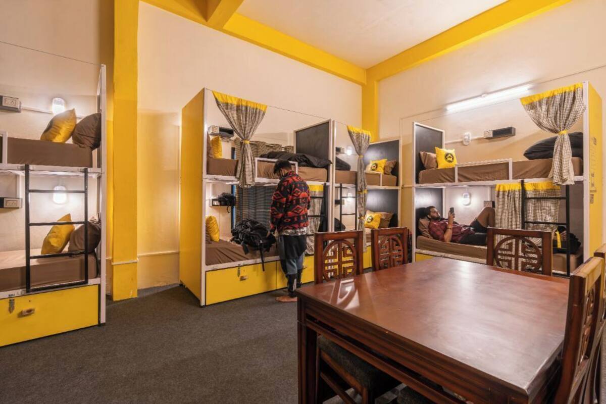 A room with bunk beds, a wooden dining table, and chairs.