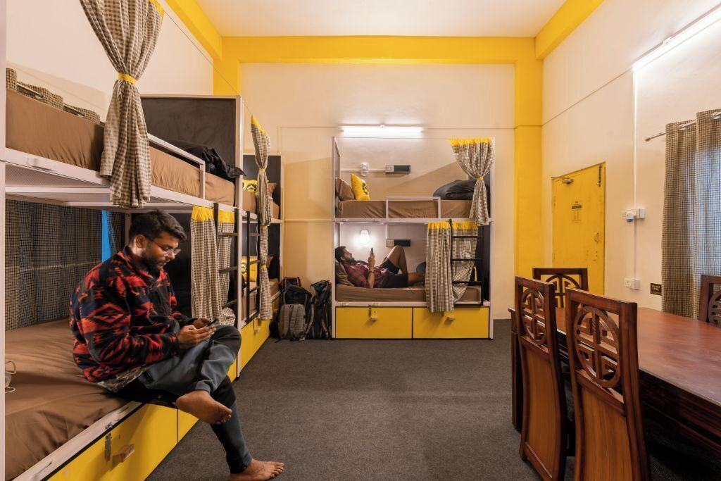 A dormitory room with bunk beds, a dining table, and chairs.