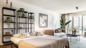 A modern bedroom with a bed, a sofa, a coffee table, and a large window.