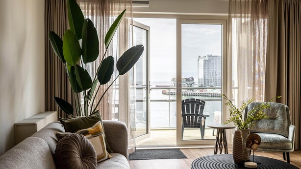 A modern living room with a sofa, a chair, a table, and a large plant.