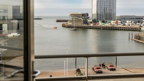 A view of a waterfront with a building under construction, a dock, and several boats.