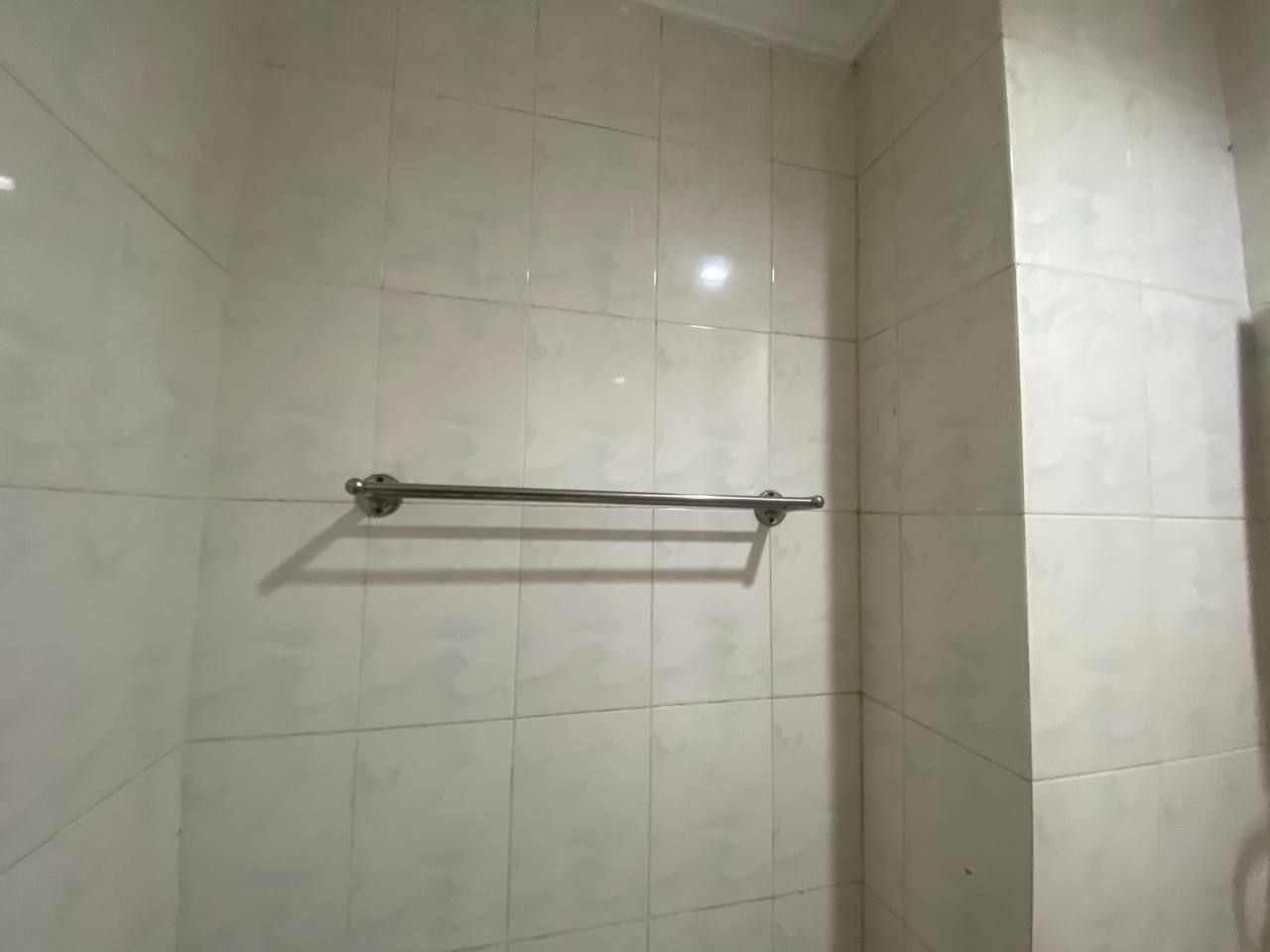A tiled shower area with a metal towel rack.
