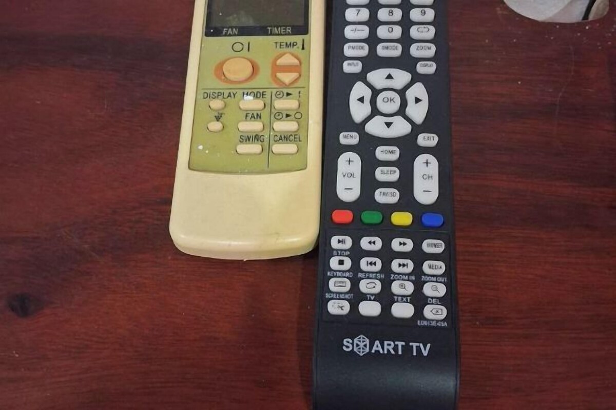 Two remote controls, one with a yellow and green color scheme and the other black, on a wooden surface.