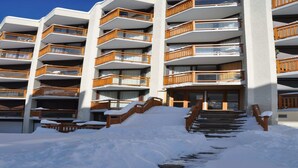 A multi-story hotel with wooden balconies and a snow-covered entrance.