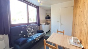 A compact living space with a sofa, a small kitchen area, and a dining table.