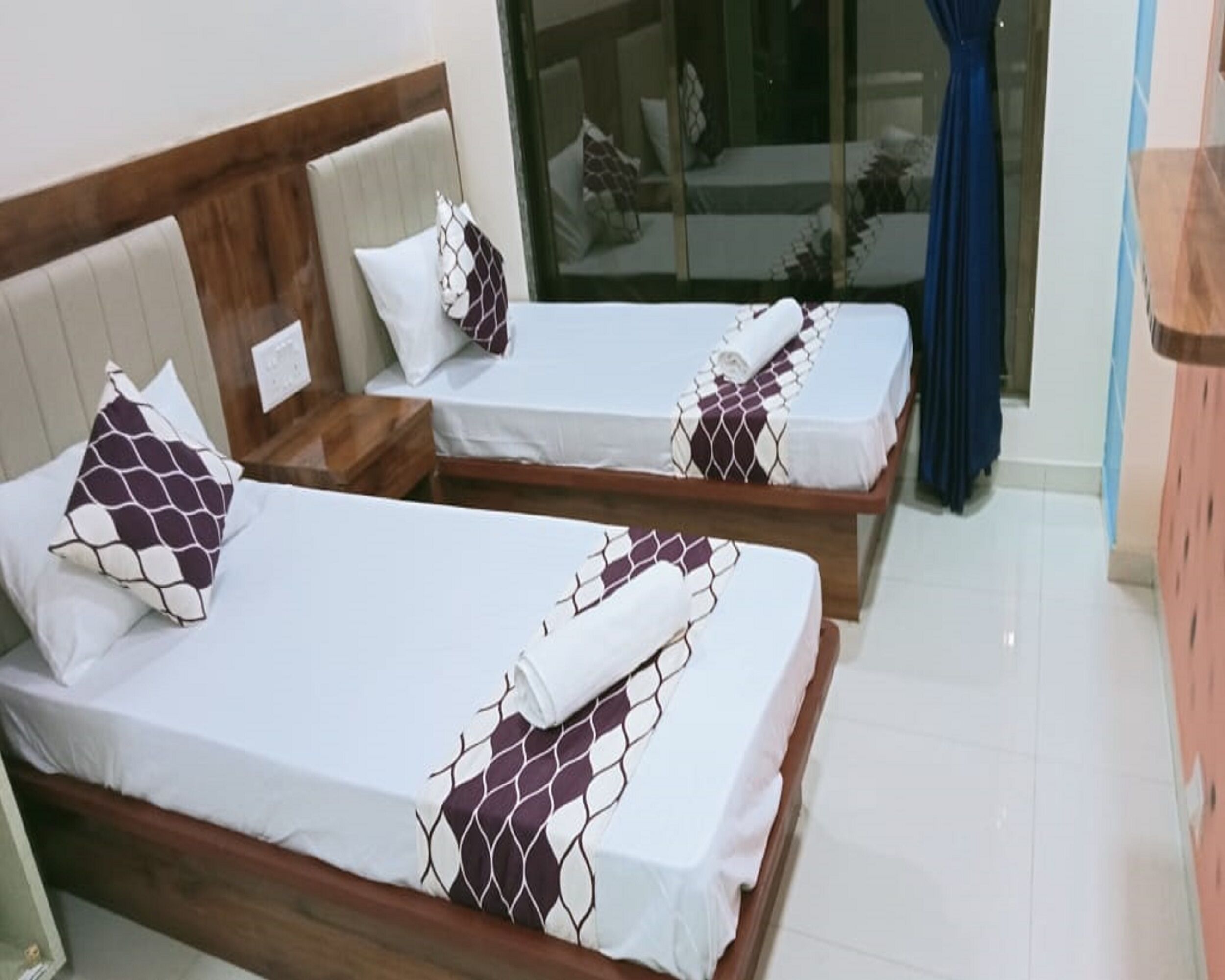 Two single beds with wooden frames and headboards, white bedding, and patterned pillows.