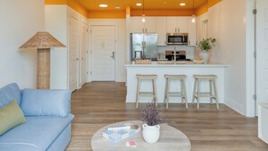 Una cocina moderna con armarios blancos, electrodomésticos de acero inoxidable y una isla central con taburetes.
