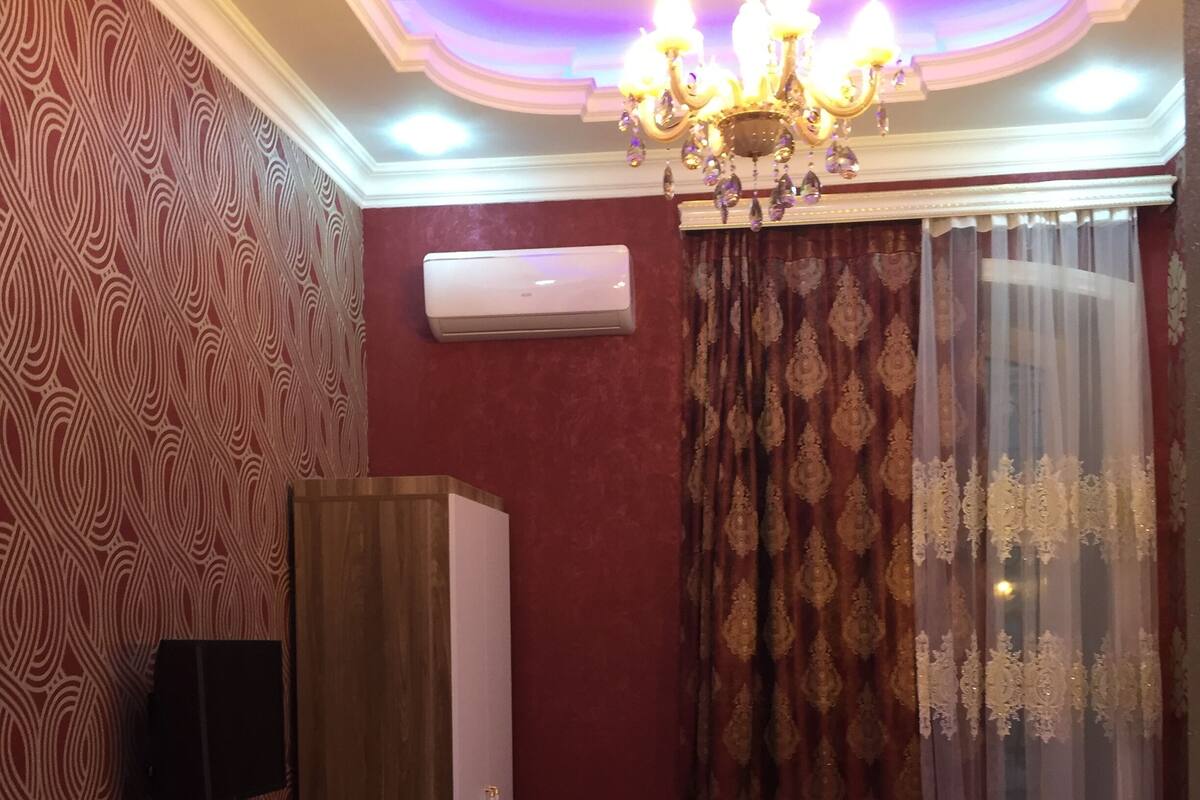 Una camera d'albergo con un letto, un armadio, un condizionatore d'aria, una televisione e un lampadario.