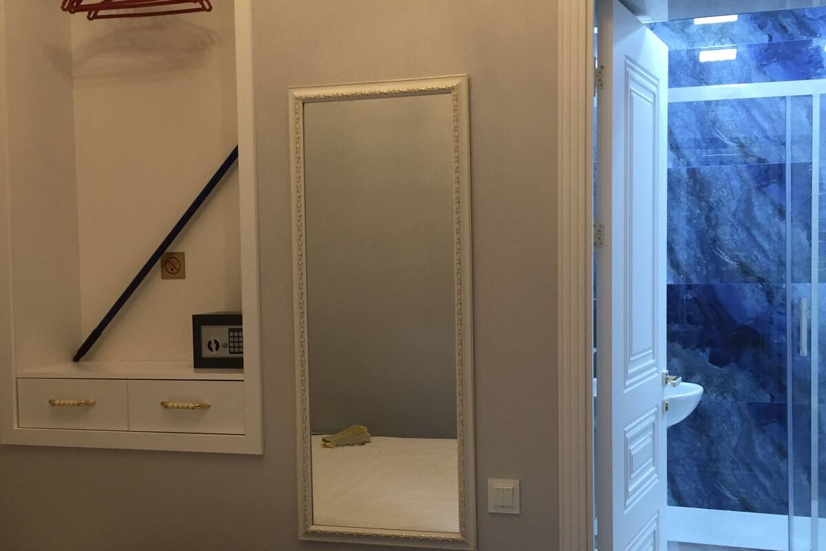 Una camera da letto con un letto, un comodino, uno specchio e un bagno parzialmente visibile attraverso una porta aperta.