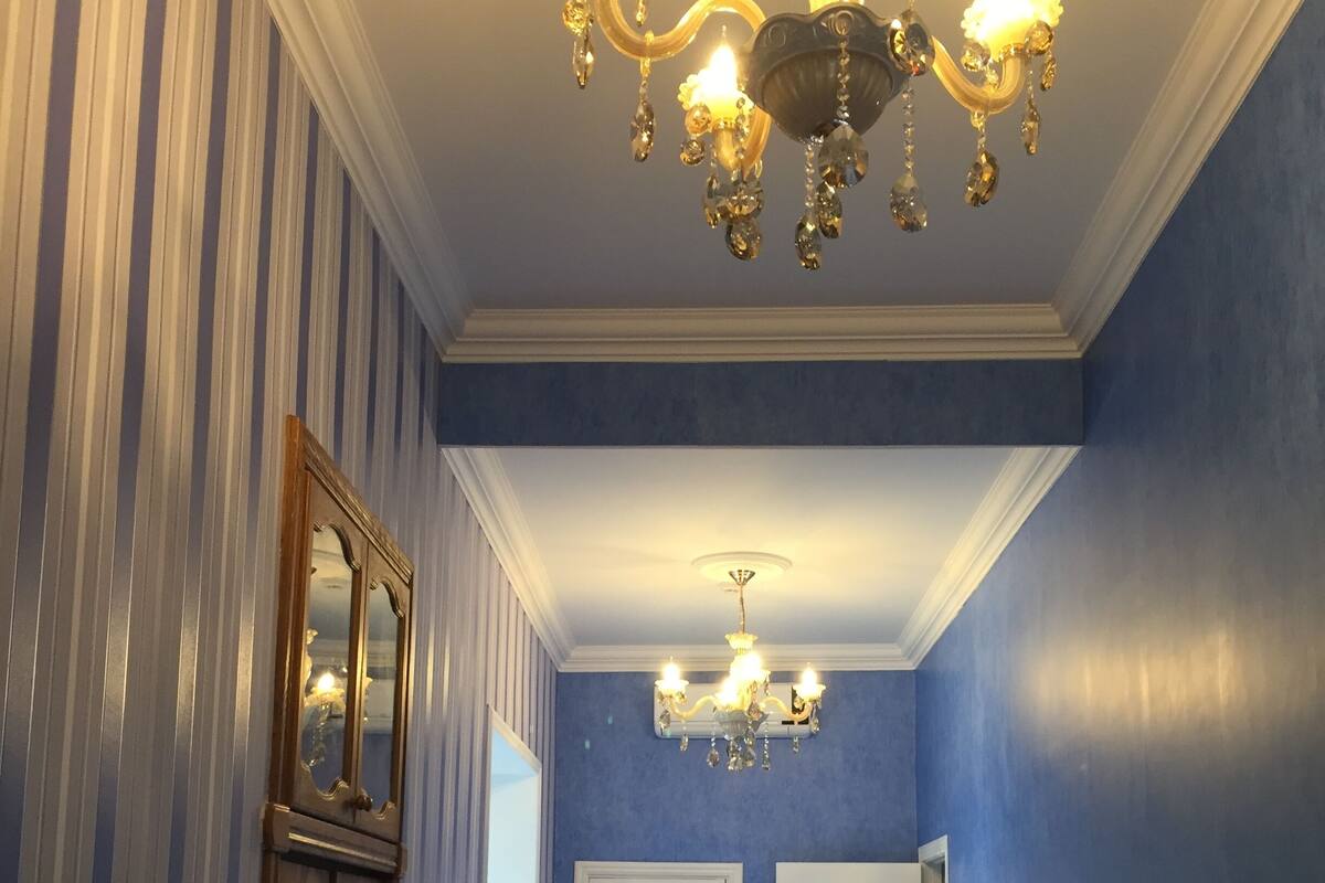 Una camera d'albergo con un letto grande, una TV, un lampadario e carta da parati a righe.