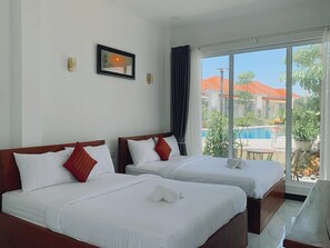 A hotel room with two beds, a large window, and a view of a swimming pool and buildings. - Kampot Orkide Boutique (Kampot)