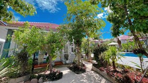 A courtyard with a pool, surrounded by lush greenery and a building with a red-tiled roof. - Kampot Orkide Boutique (Kampot)