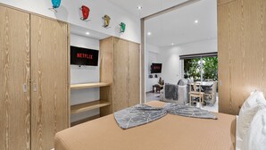 Een moderne slaapkamer met een groot bed, een houten garderobe en een aan de muur bevestigde televisie.